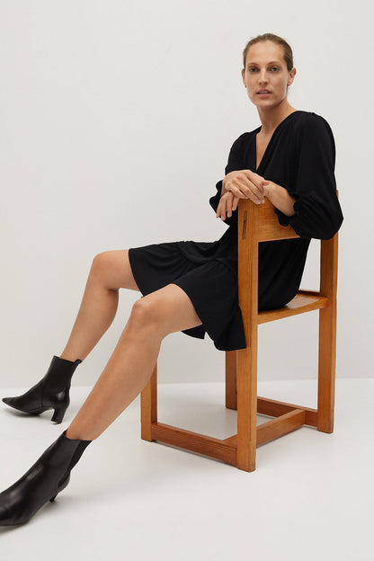 Black long-sleeve mini wrap dress with tiered skirt and gathered waist, side view