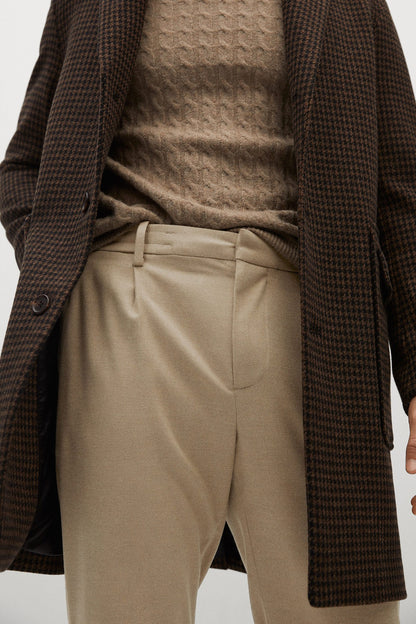 Beige trousers close-up with waistband, side pockets, and crease details
