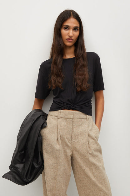 Black short-sleeve wrap-style top with beige wide-leg trousers, front view