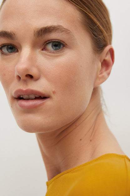 Mustard yellow short-sleeve crew-neck top, close-up on neckline and shoulder