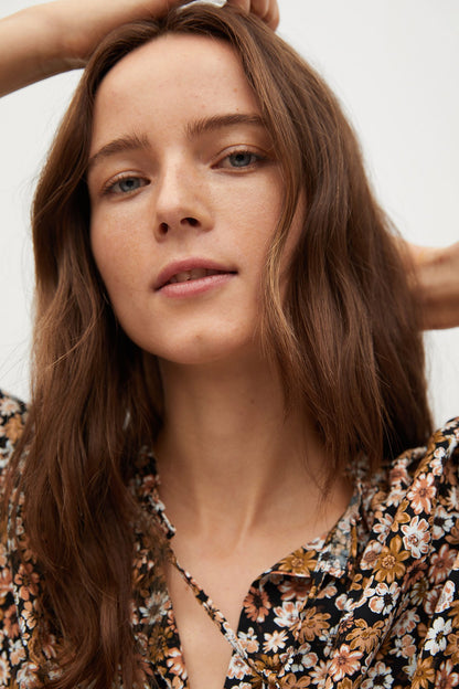 Floral V-neck top with ruched trim and long sleeves, close-up neckline detail