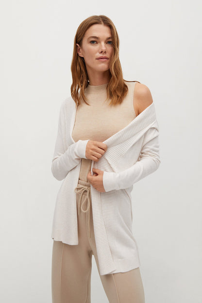Ecru knit cardigan draped over shoulders with long sleeves and waist tie