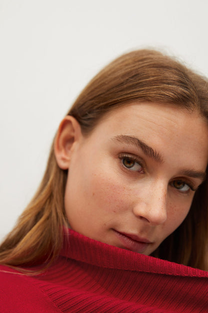 Red ribbed knit turtleneck collar detail on textured fabric