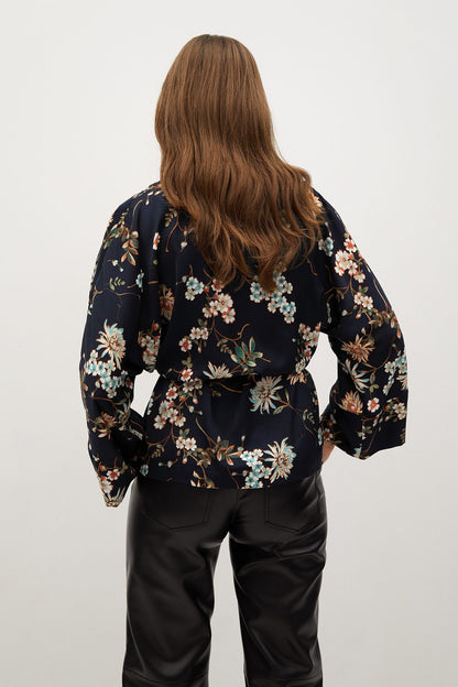 Back view of floral long-sleeve wrap blouse with tie belt at waist; dark base