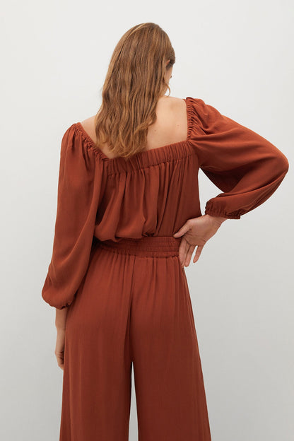 Burnt orange back view square-neck jumpsuit with gathered shoulders and belt ties
