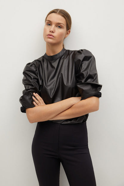 Black high-neck blouse with puff sleeves and skinny black trousers, front view