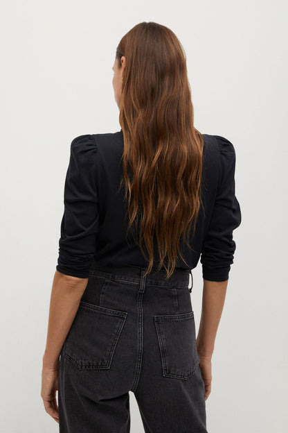 Black knit turtleneck top with long sleeves and puffed shoulders (back view)