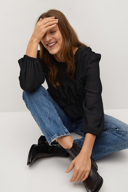 Black puff-sleeve blouse with elastic waist, seated side view