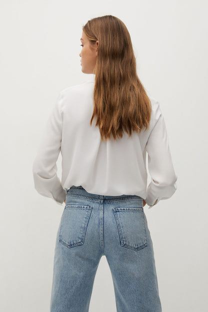 Off-white button-up blouse seen from back with long sleeves and cuffs