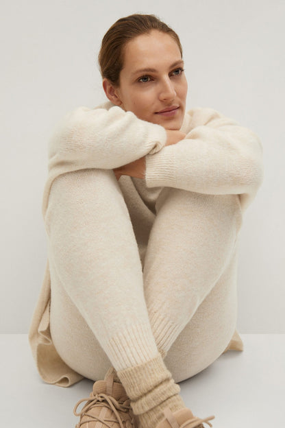 Ecru knit sweatshirt and jogger set, ribbed cuffs and waistband, hands on knees