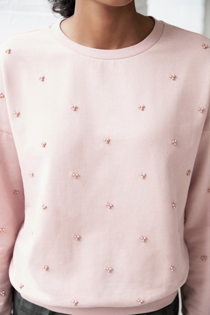 Pink crewneck sweatshirt with allover bow pattern close-up