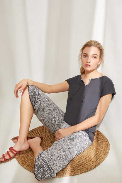 Charcoal grey pajama top with printed capri pants, seated relaxed pose
