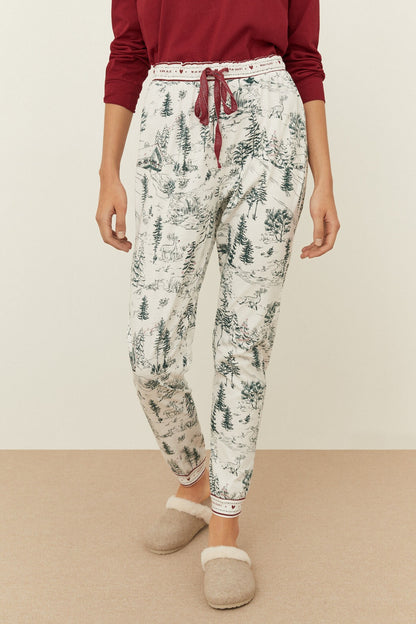 Off-white pajama pants with green forest print, red drawstring tie, elastic cuffs