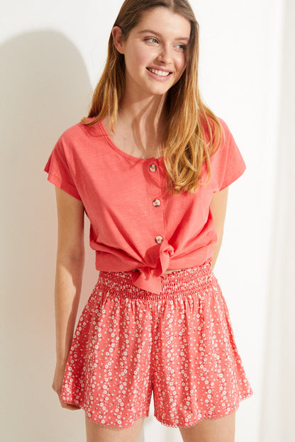 Coral pink top with button placket and red ditsy-print ruched shorts