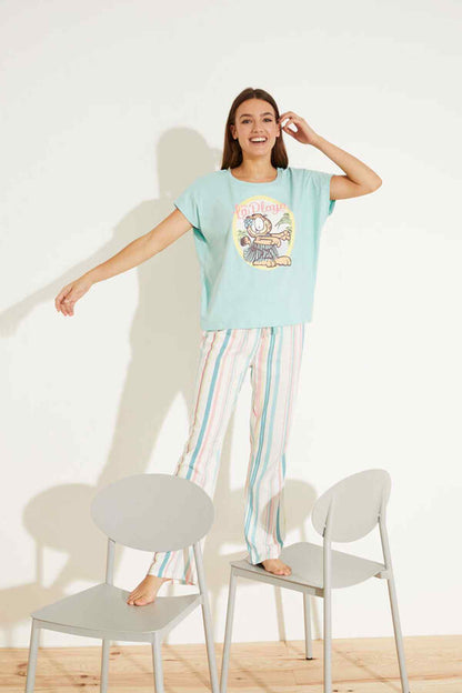 Women'secret light blue pajama top and multicolor vertical stripe pants, standing pose