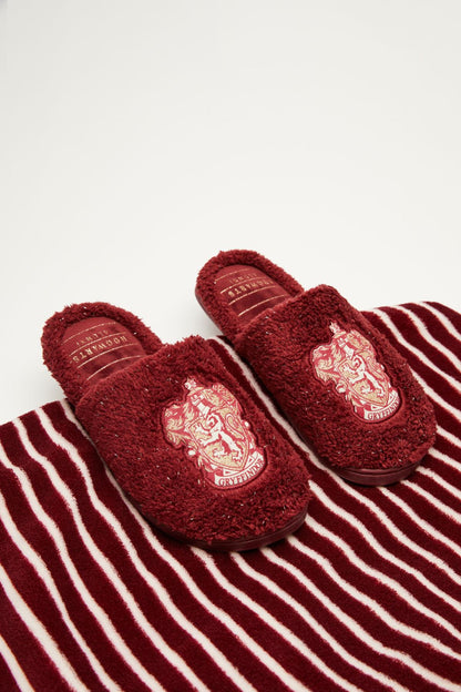 Dark red fuzzy slippers showing embroidered crest on striped fabric