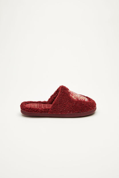Dark red fuzzy closed-back slippers with embroidered crest badge