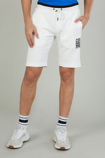 White drawstring shorts with elastic waistband and logo print on right leg, knee length