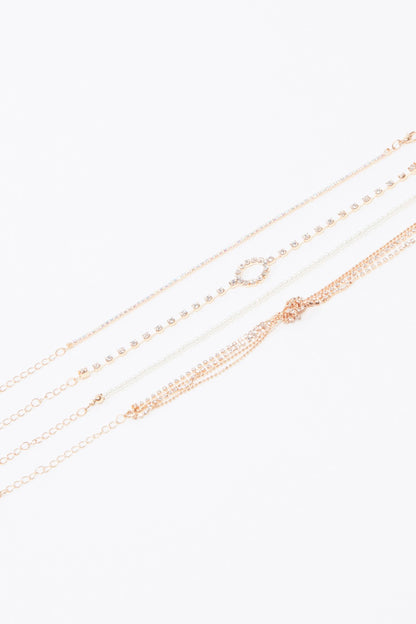 Layered gold-tone chain necklace with small charm links and circular pendant