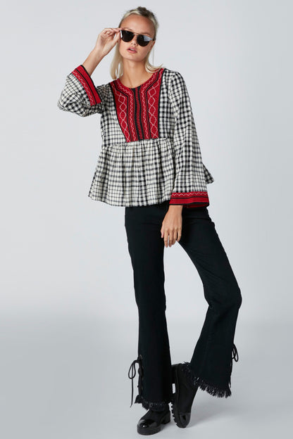 Black-and-white checked peplum blouse with red embroidered yoke and trim
