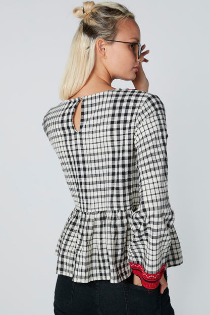 Checked peplum blouse with black-and-white pattern, red neckline and sleeve cuffs