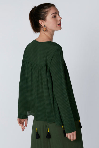 Green long-sleeve midi dress, side view, with colorful tassel trim at hem