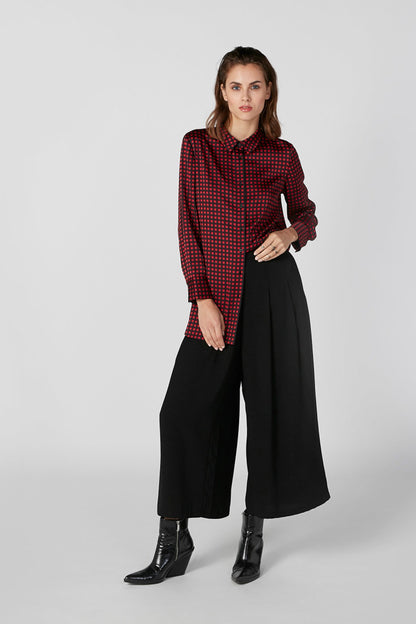 Red patterned button-up blouse, long sleeves, worn with black wide-leg pants