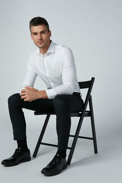 Men's white long-sleeve button-up dress shirt, seated full-body view.
