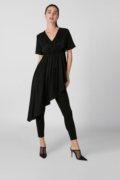 Women's black V-neck short-sleeve tunic dress with asymmetrical hem, worn over leggings