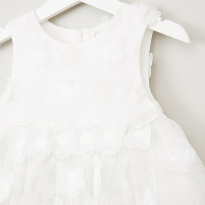 White sleeveless baby dress close-up with textured bodice and layered floral ruffles